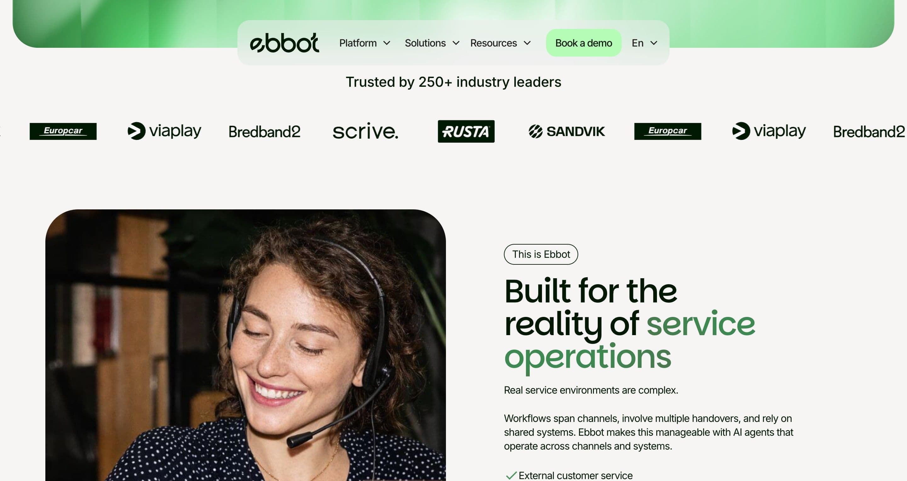 The intro section on ebbot.com, a smiling support agent with a headset below a row of customer logos